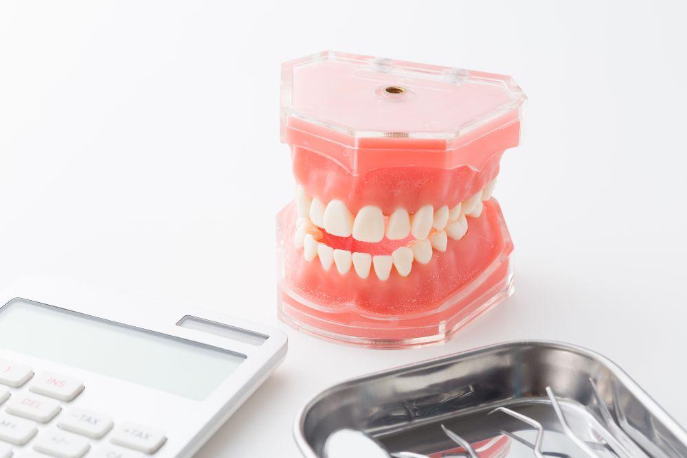 歯の模型と電卓と治療器具